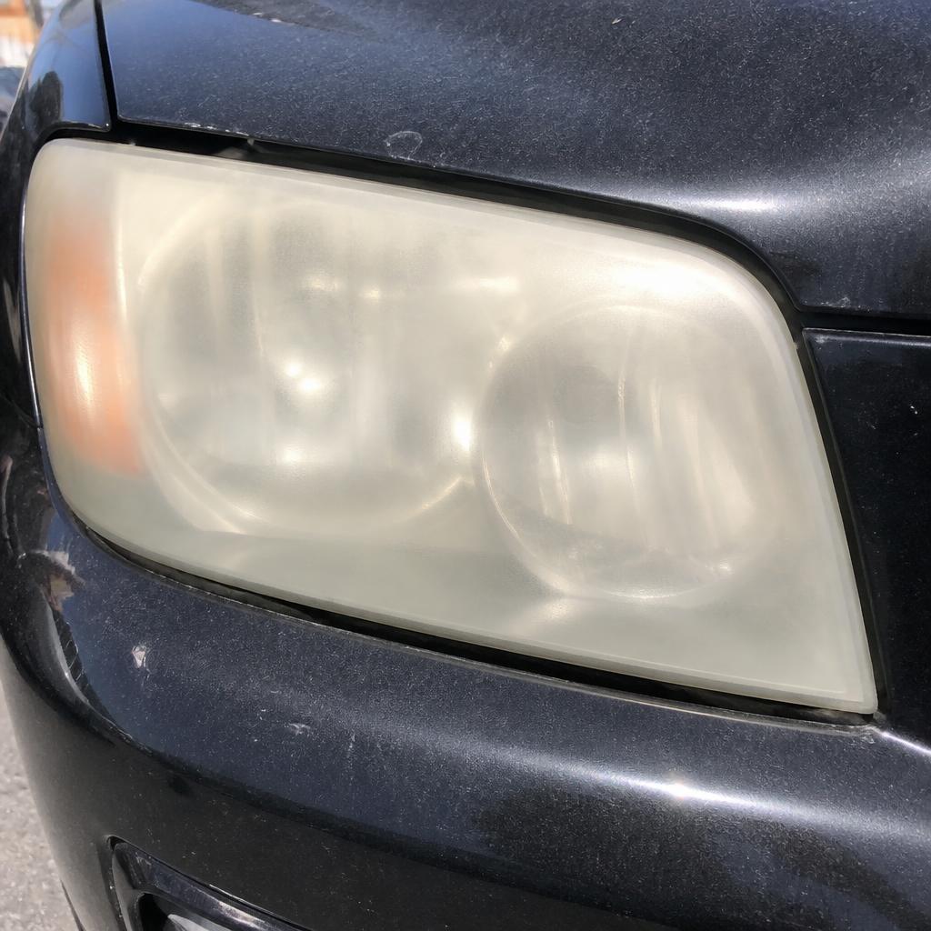 Black SUV headlight before restoration